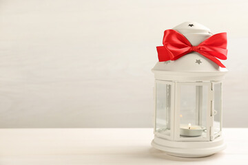 Beautiful decorative Christmas lantern with burning candle on white wooden table. Space for text