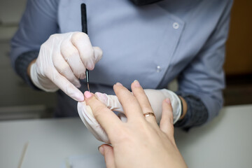 Obraz na płótnie Canvas client is undergoing a procedure with a manicure master. Manicurist apply gel polish to nails
