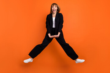 Full size photo of happy crazy smiling good mood positive active energetic girl jumping isolated on orange color background