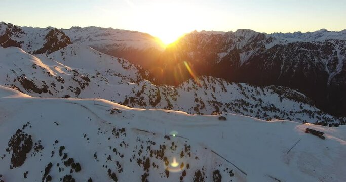 French alps at Chamrousse with sunrise between the snowy peaks, Aerial flyover approach shot
