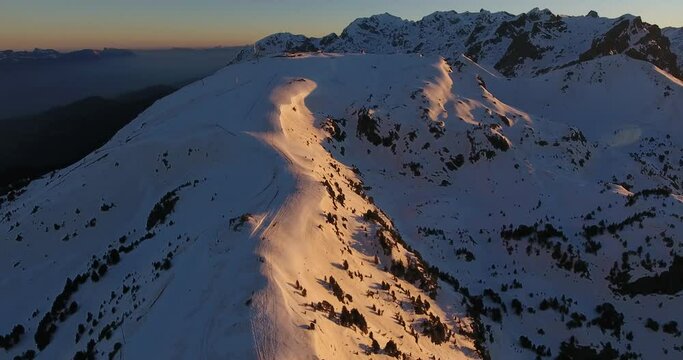 Ski downhill track at Chamrousse on the French Alps during sunrise, Aerial orbit shot
