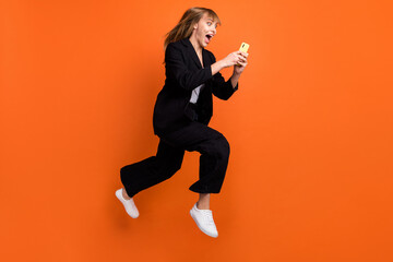 Fototapeta na wymiar Full size profile side photo of happy crazy smiling woman see huge sale discount in phone isolated on orange color background
