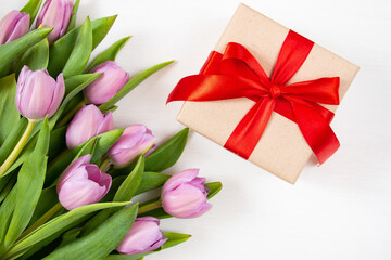 Tulips and gift box on a white background. Festive floral concept with clean text space. Flat lay. View from above.