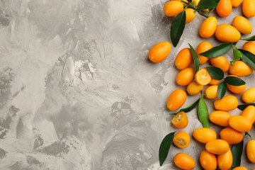 Fresh ripe kumquats on light grey table, flat lay. Space for text