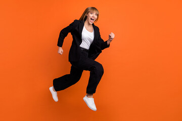 Fototapeta na wymiar Full size profile side photo of happy excited smiling good mood girl running fast in air isolated on orange color background