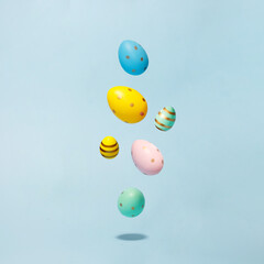 Colored easter decorated eggs flying on a blue background. Easter greeting card in minimalist style concept.Copy space