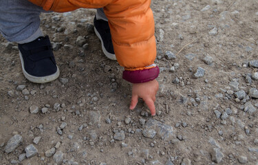 Toddler picking up a stone from the ground (human hand)