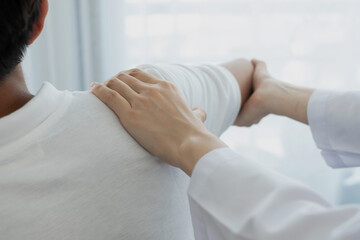 Female physiotherapists provide physical assistance to male patients with shoulder injuries massage their shoulders for muscle recovery in the rehabilitation center. Physiotherapy concepts