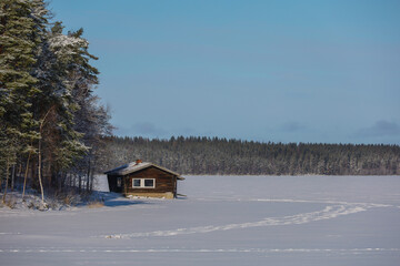 Winter landscape with a Finnish sauna by the lake