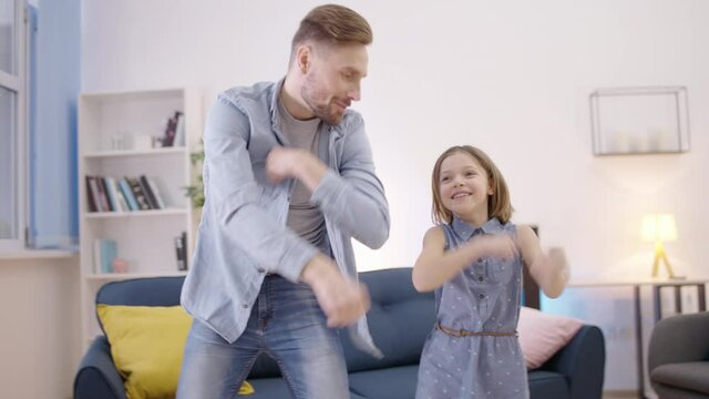 Carefree parent and child dancing together, dad spending time with daughter
