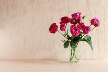 Beautiful tender pink roses in glass vase on the table with copy space. Minimal home decor. Festive floral backround