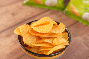 Bowl with tasty potato chips on wooden background .