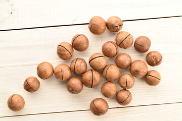 Several ripe brown macadamia nuts, close-up, on a wooden table.