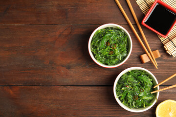 Japanese seaweed salad served on wooden table, flat lay. Space for text