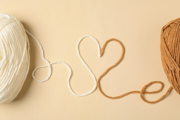Heart made with threads and woolen yarns on beige background, flat lay