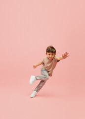 Fototapeta na wymiar Flying high. Happy, smiley little caucasian boy isolated on pink studio background with copyspace for ad. Looks happy, cheerful. Childhood, education, human emotions, facial expression concept.