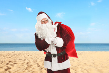 Santa Claus with sack on beach near sea. Christmas vacation