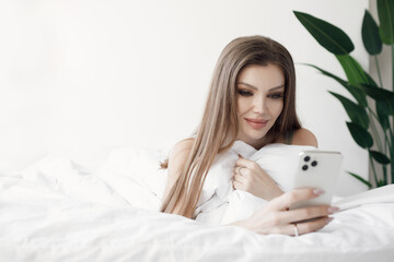 Beautiful woman in bed with phone