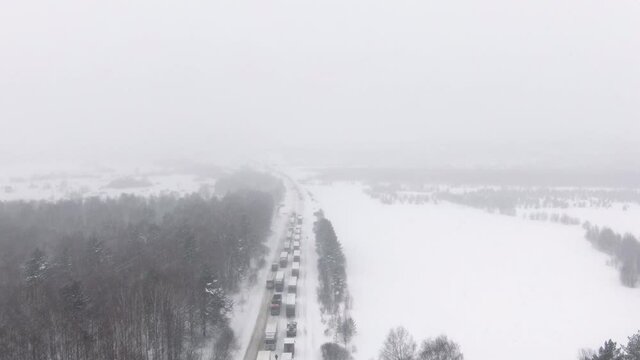 Trucks are stuck in traffic on a snow-covered highway. Thousands stranded on highway as major snowstorm and blizzard hits hard causing