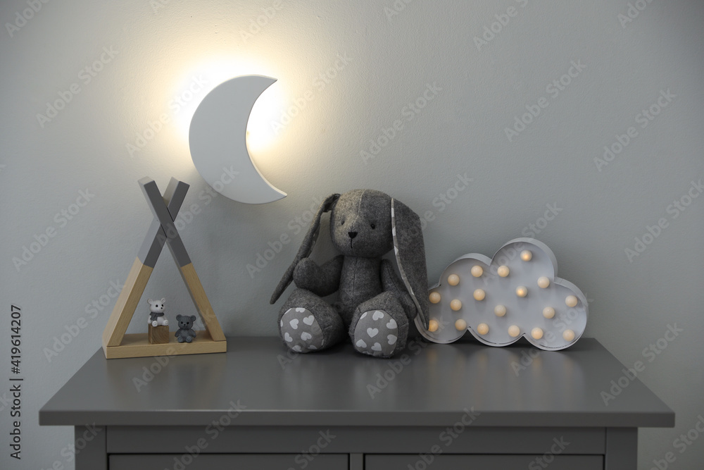 Sticker crescent shaped night lamp above cabinet with toys