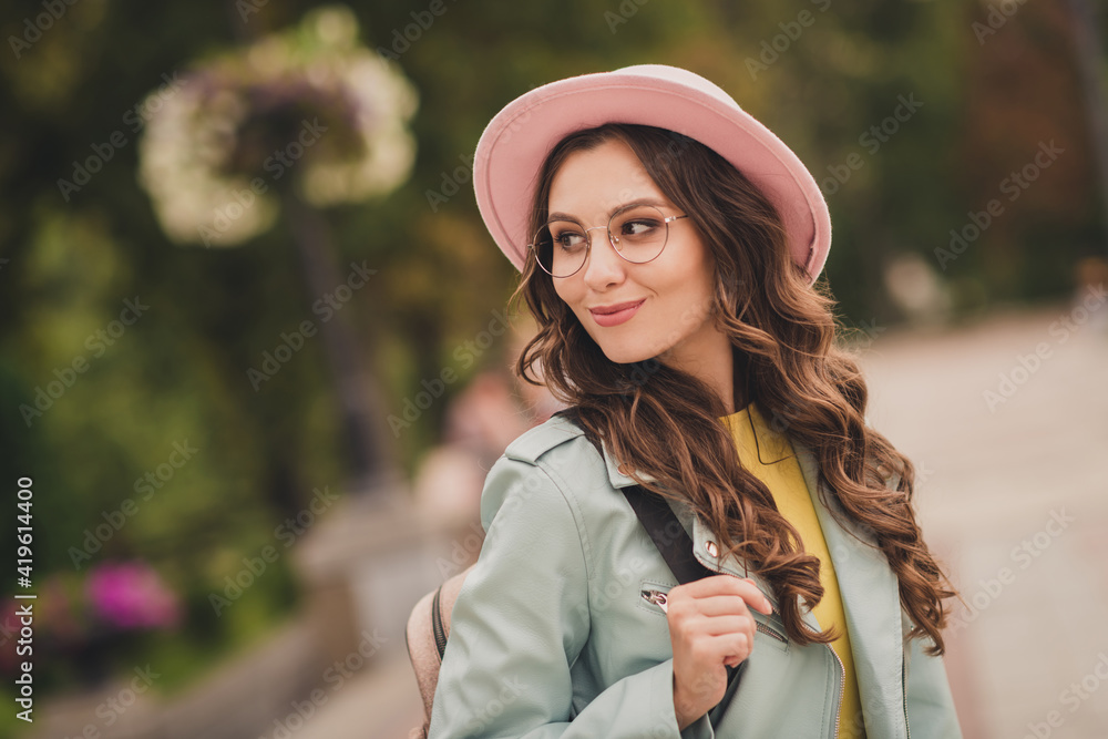 Poster photo of cute charming young lady wear turquoise jacket rucksack cap spectacles walking looking back