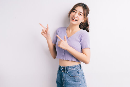 Cheerful young Asian girl pointing on white background
