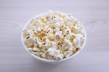 Salted popcorn in a bowl on a wooden table. Top view