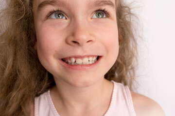 Attractive little girl stands on a white background with empty copy space, happy expression on her...