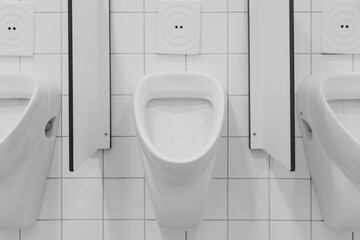 seperated urinals at public restroom with white seperation between and automatic infrared flushing