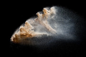 Sand explosion isolated on black background. Freeze motion of sandy dust splash.