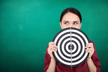 Beautiful businesswoman portrait holding round target of darts