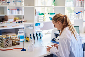 Female lab technician analyzing a sample in a petri dish