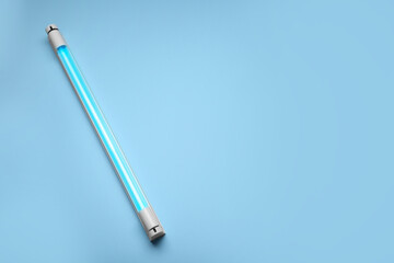 Ultraviolet lamp on light blue background, top view. Space for text