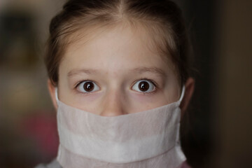 Little european girl wearing mask for protect pm2.5 and Covid-19. Sick child Little girls look at the camera posing in the studio in a red dress with a medical mask on her face.