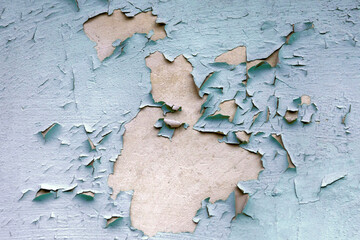 Old and flaking blue paint on the wall. Texture of old peeling paint, weathered rough painted surface, cracked texture.