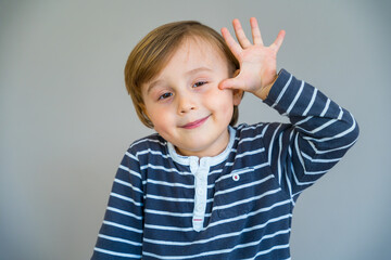 Adorable little toddler boy showing five fingers in the palm of his hand. Child smiling. Early...