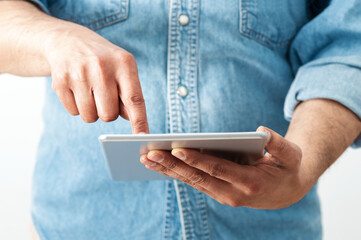 Cropped shot of an unrecognizable businessman standing alone in his home office and surfing on his digital tablet