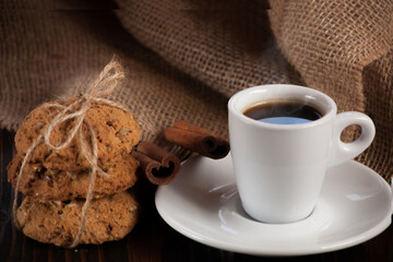 A cup of aromatic black coffee. Morning espresso or Americano coffee for breakfast in a beautiful cup. Cinnamon sticks. Wooden background. Russian gingerbread. 