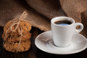 A cup of aromatic black coffee. Morning espresso or Americano coffee for breakfast in a beautiful cup. Cinnamon sticks. Wooden background. Russian gingerbread. 