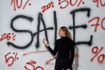 Woman painting graffiti on wall using paint sprayer