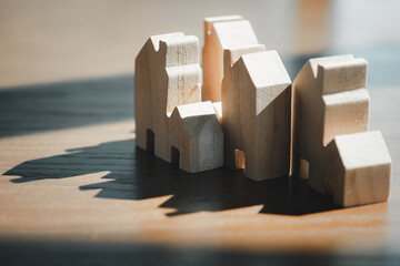 Group of mini wooden home model placed on wooden table with lighting morning and shadow.