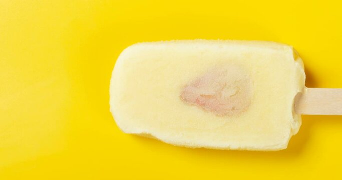 4K DCI standard resolution ratio of durian flavor popsicle with slice of strawberry melting on a yellow background timelapse