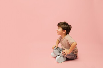 Dreaming, smiling. Happy, smiley little caucasian boy isolated on pink studio background with copyspace for ad. Looks happy, cheerful. Childhood, education, human emotions, facial expression concept.
