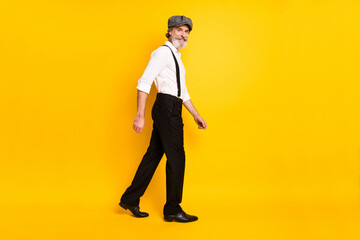 Full body profile side photo of mature man happy positive smile go walk step empty space isolated over yellow color background