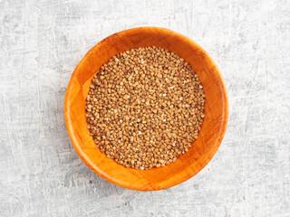 Buckwheat in a wooden bamboo cup on a white concrete background