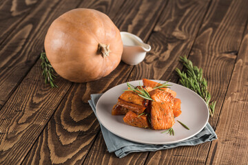 Baked pumpkin with rosemary on a plate with a napkin on a wooden background. Food for the diet.