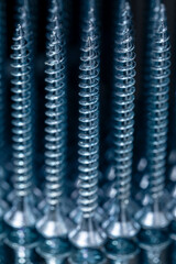 Standing galvanized self-tapping screws on a mirror surface. Screws macro photo. Construction abstraction. Industrial background.