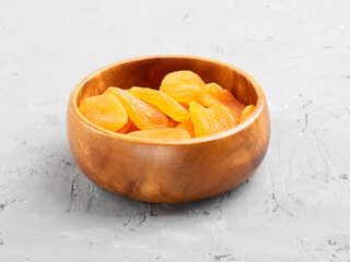 Dried apricots in a wooden bowl on concrete background
