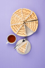 A few pieces of cheesecake on a plate with a cup of tea on a colored background. A delicious dessert for a birthday and holiday.