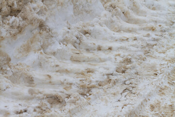 The texture of dirty snow on the road with a trail from a bulldozer
